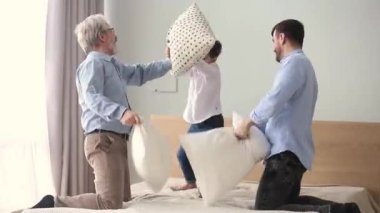 Mutlu üç nesil erkek aile yatakta yastık mücadele olan