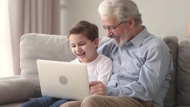 Щасливий старий дід і маленький онук сміється, дивлячись на ноутбук — стокове відео
