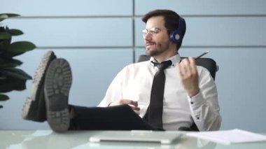 Mutlu işadamı işyerinde müzik dinlerken kulaklık takıyor