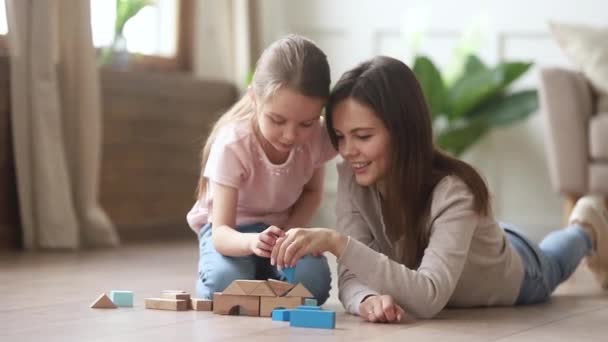 Mom helping kid daughter playing building castle from wooden blocks — Stock Video