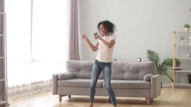 Evde müzik dinleyerek akıllı telefon dans tutan Afrikalı kadın