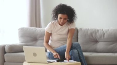Ciddi Afrikalı kadın dizüstü bilgisayarda online yurtiçi faturaları ödeyerek hesaplanması
