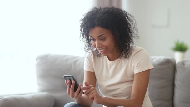 Feliz jovem Africano americano mulher vencedora gritando olhando para smartphone — Vídeo de Stock