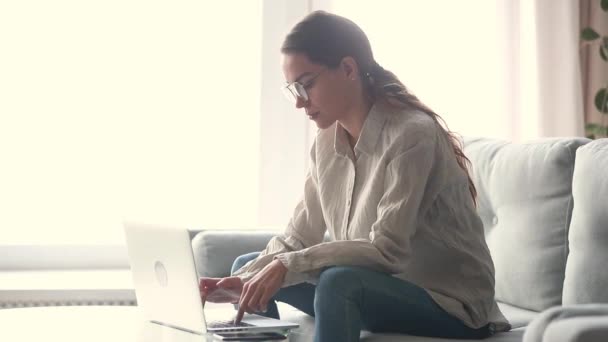 Freelancer jovem focado trabalhando em casa digitando no laptop — Vídeo de Stock