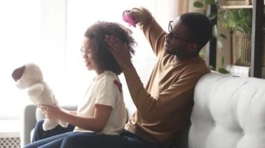 Sevgi dolu siyah baba çocuk kızı afro saç fırçalama yapıyor
