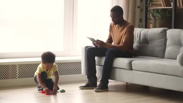 Padre africano e hijo pequeño pasan tiempo en la sala de estar — Vídeo de stock