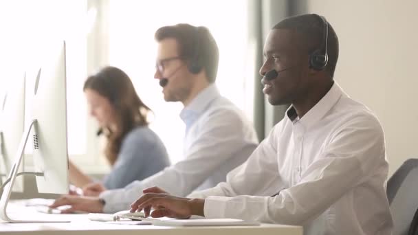 Focused african call center agent wear wireless headset consulting customer — Stock Video