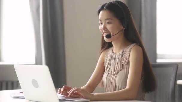 Asiatico donna d'affari receptionist indossare auricolare consulenza cliente sul computer portatile — Video Stock