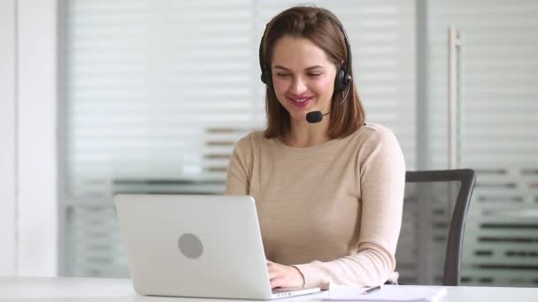Uśmiechnięta biznesu kobieta recepcjonistka nosić zestaw słuchawkowy skonsultować się z klientem online — Wideo stockowe