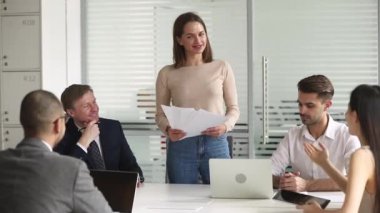 Çalışanlarla konuşan belgeleri tutan kadın yönetici toplantıda toplandı