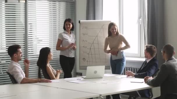 Dois alto-falantes do sexo feminino diversos dar apresentação de negócios no gráfico flip — Vídeo de Stock