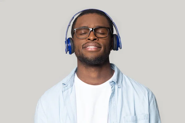 Sorrindo homem negro em óculos desfrutar de música em fones de ouvido Bluetooth — Fotografia de Stock