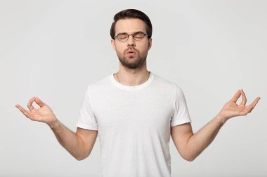 Gözlüklü genç adam gri izole nefes egzersizleri yapıyor