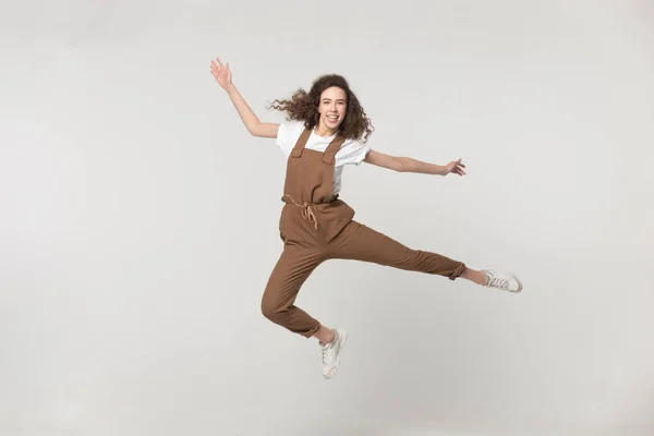 Lycklig aktiv kvinna hoppar i studion isolerad på grå bakgrund — Stockfoto