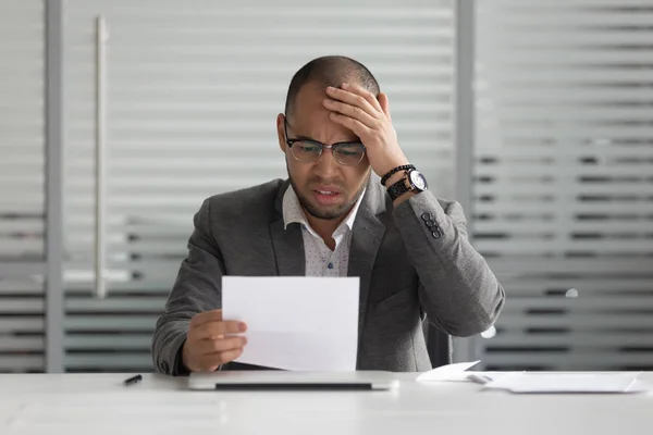 Frustrado molesto empresario africano leyendo malas noticias en carta de correo — Foto de Stock