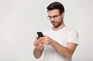 Man wearing glasses pose on grey background using mobile phone clipart
