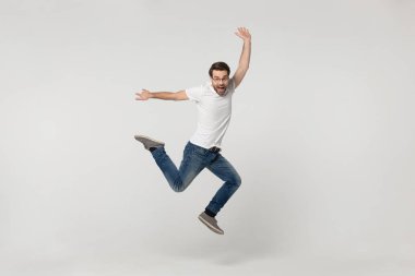 Canlı adam gri arka planda izole atlama kamera bakmak