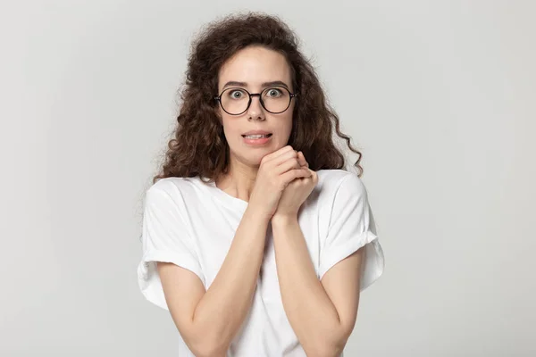 Verängstigte junge Frau blickt in die Kamera und posiert auf grauem Hintergrund — Stockfoto