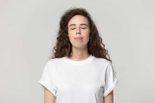 Mujer ojos cerrados disfrutar de la pose de aire fresco aislado en gris — Foto de Stock