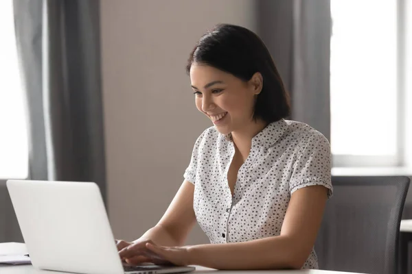 Sorrindo asiático empresária usando computador digitando sentado na mesa de trabalho — Fotografia de Stock