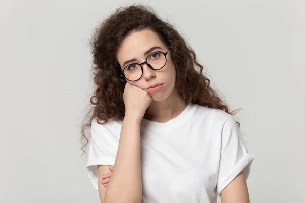 Gelangweilte junge Frau posiert auf grauem Studiohintergrund — Stockfoto