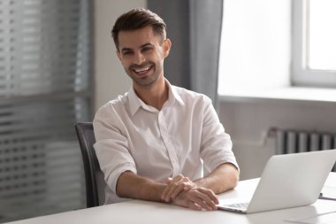 Neşeli genç iş adamı iş ofis masasında oturan gülüyor
