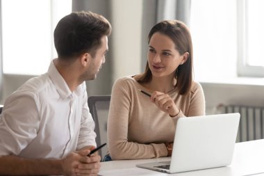 İş yerinde konuşan yaratıcı erkek ve kadın iş arkadaşları fikirlerini paylaşıyor