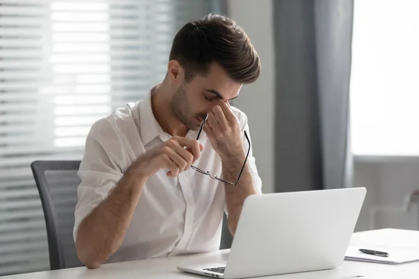 Überlasteter gestresster Geschäftsmann mit Brille massiert Nasenbrücke — Stockfoto