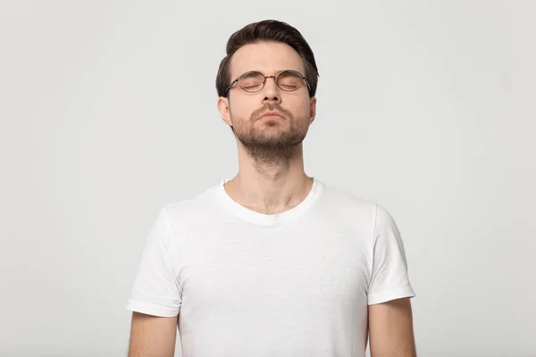 Jeune homme les yeux fermés rêvant isolé sur fond de studio gris — Photo