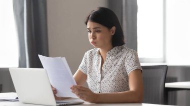 Stresli asyalı iş kadını kağıt üzerinde kötü haber okuma üzgün