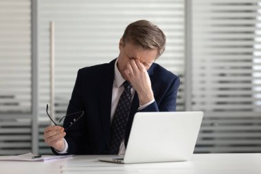 Aşırı çalışan stresli işadamı bilgisayar iş yorgun gözlük çıkarmak