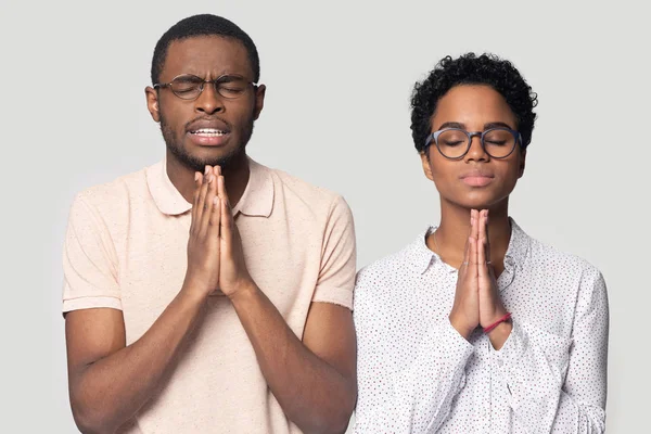 Hopeful ethnic man and woman hold hands in prayer — Stock Photo, Image