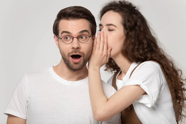 Girlfriend whispering in ear to boyfriend a secret studio shot — Stock Photo, Image