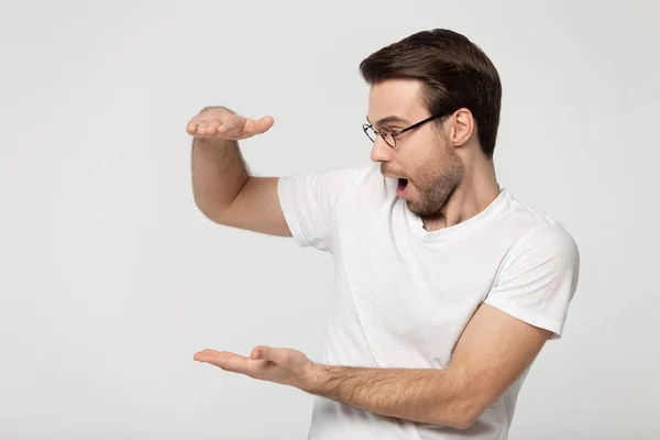 Shocked man show with hands big size feels amazed