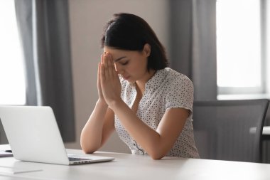 Odaklanmış Asyalı iş kadını iş yerinde dua ellerini koymak