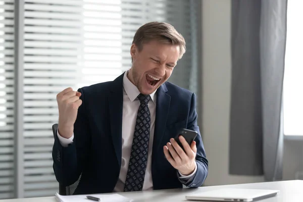 Euphoric happy businessman wear suit celebrate mobile win — Stock Photo, Image