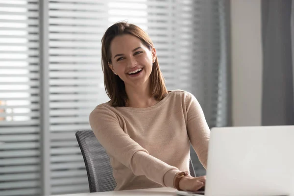 Lycklig ung affärskvinna skrattar sittande vid arbetsbord med laptop — Stockfoto