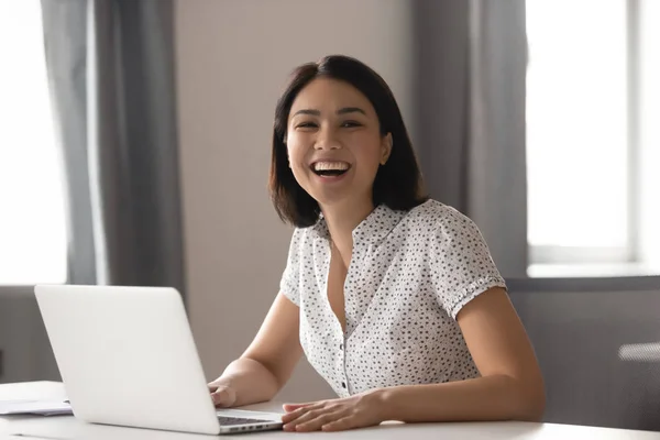 Feliz asiático mujer de negocios riendo sentado en el escritorio con el ordenador portátil —  Fotos de Stock
