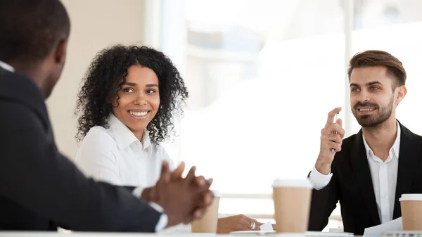 Interested diverse employees listening to colleague talk at briefing