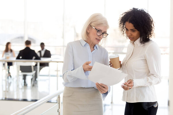 Mujer de negocios madura seria mostrar documento a colega afroamericano — Foto de Stock