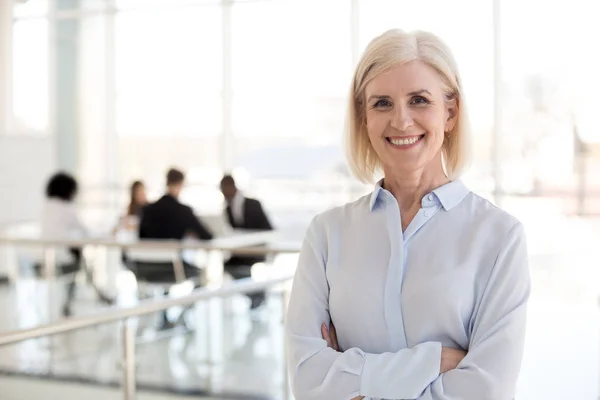 Testa ritratto sorridente donna d'affari matura in posa nel corridoio ufficio — Foto Stock