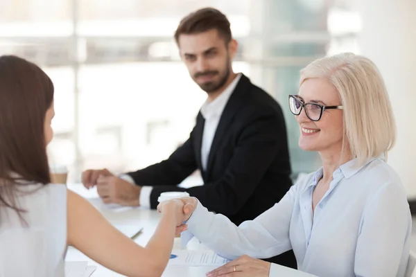 Sonriente mujer de negocios madura estrechando la mano de colega en la reunión — Foto de Stock