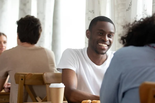 Счастливый улыбающийся черный парень сидит в кофейне с другом . — стоковое фото
