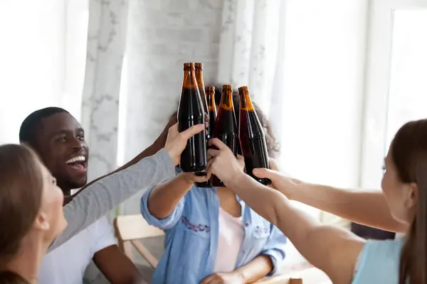 Nahaufnahme fröhliche gemischte Rassenmenschen, die Flaschen mit Bier klappern. — Stockfoto