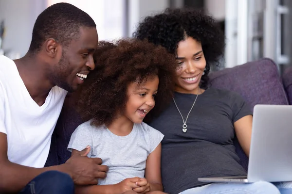 Afrikaanse familie met kleine dochter zittend op de Bank met behulp van computer — Stockfoto