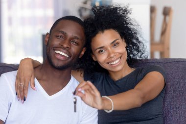 Afrikalı çift kanepede oturan yeni evden anahtarları tutarak