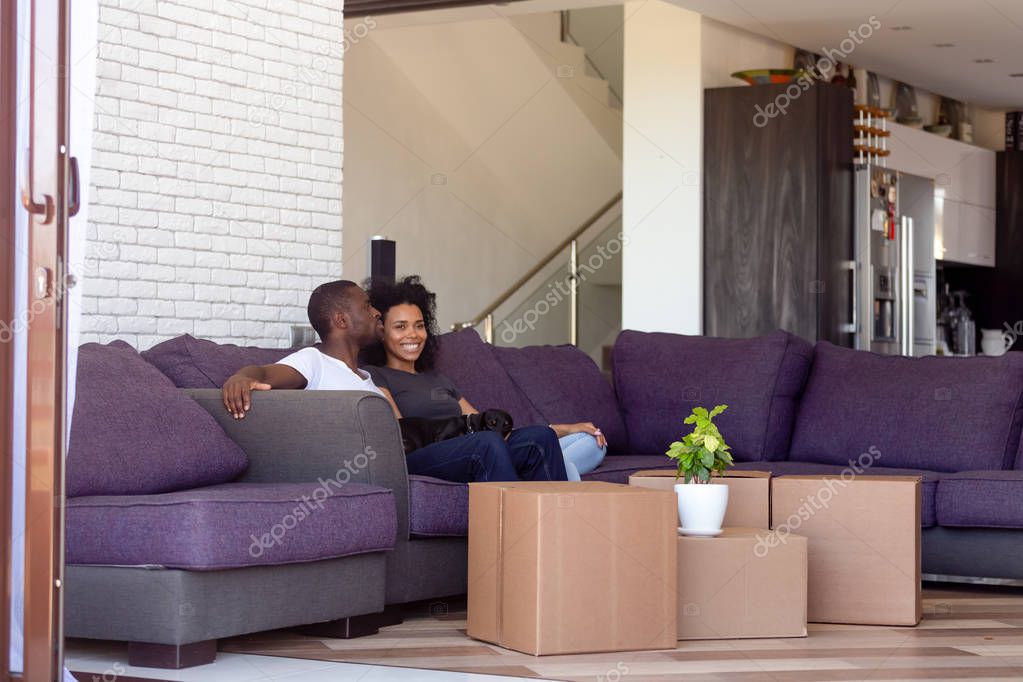 Millennial spouses resting in spacious living room on relocation day