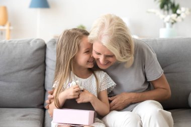 Neşeli büyükanne ve torun oturan birlikte kanepede gülüyor