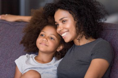 Küçük anaokulu kızı ile kanepede oturan Afrikalı anne