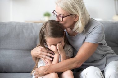 Büyükanne kanepede oturan sinirli torununu kucaklamak